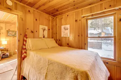 a bed in a wooden room with a window at Close to Lake and Heavenly Mtn Resort! Quaint Cabin in South Lake Tahoe