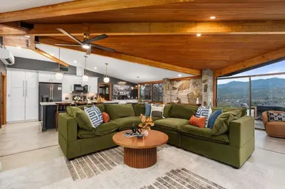 a living room with green couches and a table at New! Stunning views Hot tub King beds in Oakhurst
