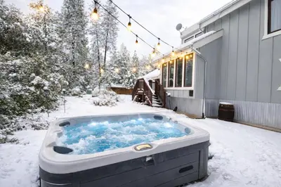 a hot tub sitting outside of a house in the snow at Vista Chalet near Yosemite and Bass Lake in Oakhurst
