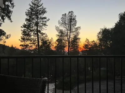a sunset over a fence with trees in the background at Vista Chalet near Yosemite and Bass Lake in Oakhurst