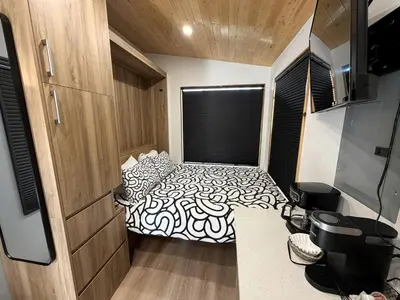 a bedroom with a bed with a black and white comforter at Stylish Modern Tiny House on Wheels with Stunning Mountain Views Near Lone Pine, California in Lone Pine