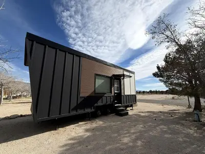 a black shipping container sitting on the side of a road at Stylish Modern Tiny House on Wheels with Stunning Mountain Views Near Lone Pine, California in Lone Pine