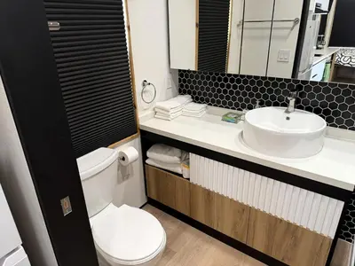 a bathroom with a white toilet and a sink at Stylish Modern Tiny House on Wheels with Stunning Mountain Views Near Lone Pine, California in Lone Pine