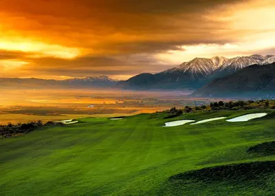 a green golf course with mountains in the background at Carson Valley Inn in Minden