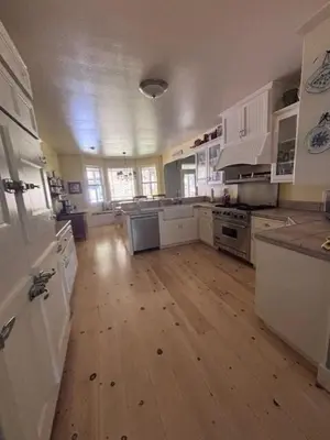a large kitchen with white cabinets and a wooden floor at The Firehouse Inn-Cottage in Mariposa