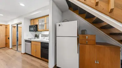 a kitchen with a white refrigerator and wooden cabinets at The Traverse by AvantStay Ski-InSki-Out Condo • Pool Hot Tub Access • Steps to KT-22 in Olympic Valley