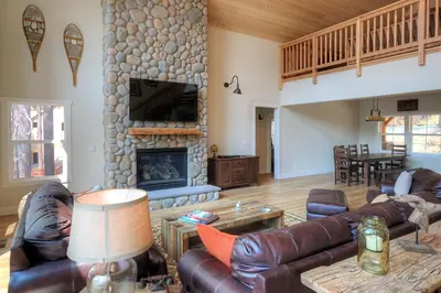 a living room with leather furniture and a stone fireplace at River Rock Retreat in Yosemite West