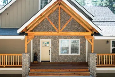 a house with a wooden front porch with a white door at River Rock Retreat in Yosemite West