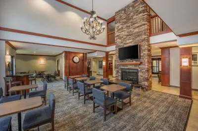 a hotel lobby with tables and chairs and a fireplace at Staybridge Suites Rocklin - Roseville Area by IHG in Rocklin