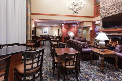 a hotel lobby with tables and chairs and a fireplace at Staybridge Suites Rocklin - Roseville Area by IHG in Rocklin