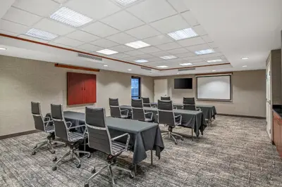 a conference room with tables and chairs and a screen at Staybridge Suites Rocklin - Roseville Area by IHG in Rocklin