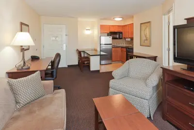 a living room with a couch and chairs and a kitchen at Staybridge Suites Rocklin - Roseville Area by IHG in Rocklin