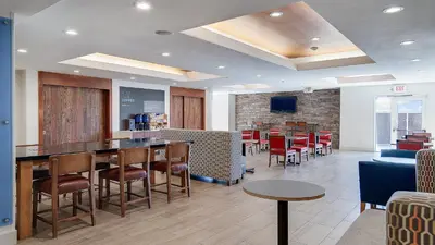 a restaurant with a bar with chairs and tables at Holiday Inn Express & Suites Dinuba West by IHG in Dinuba