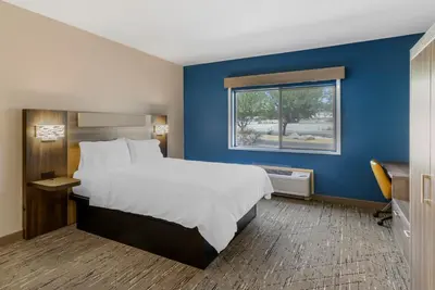 a bedroom with a large bed with a blue wall at Holiday Inn Express Fallon by IHG in Fallon