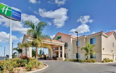 a hotel exterior with a street sign and palm trees at Holiday Inn Express Delano Highway 99 by IHG in Delano