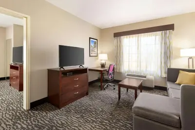 a hotel room with a couch and a desk with a television at La Quinta by Wyndham Fresno Northwest in Fresno
