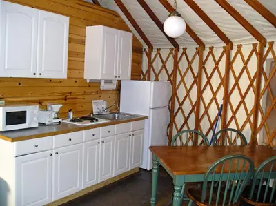 a kitchen with white cabinets and a table and a refrigerator at Yosemite Lakes Hillside Yurt 1 in Harden Flat
