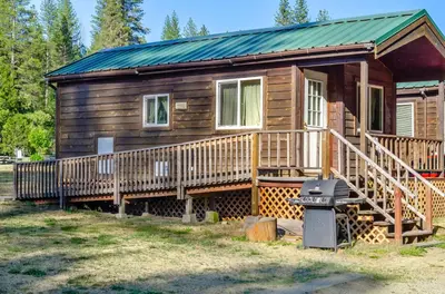 a wooden cabin with a porch and a grill at Yosemite Lakes Cabin & Cottages in Harden Flat