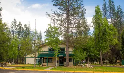 a house with a green porch and trees at Yosemite Lakes Cottage 49 in Harden Flat