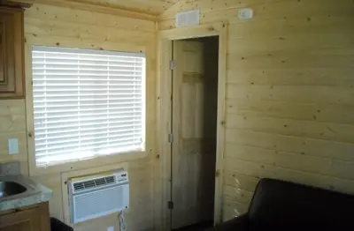 a log cabin with a window and an air conditioner at Yosemite Lakes Cottage 49 in Harden Flat