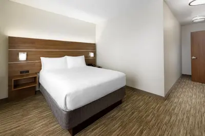 a bedroom with a white bed and a wooden headboard at Holiday Inn Express & Suites Oakhurst-Yosemite Park Area by IHG in Oakhurst