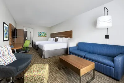 a hotel room with a bed and a blue couch at Holiday Inn Express & Suites Oakhurst-Yosemite Park Area by IHG in Oakhurst