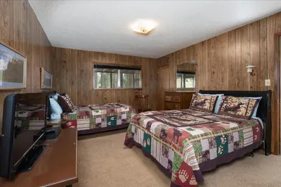 two beds in a room with wood paneled walls at PaPa Bear Cabin in North Wawona