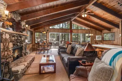 a living room with a stone fireplace in a log cabin at PaPa Bear Cabin in North Wawona