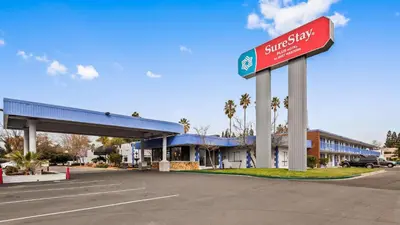 a gas station with a sign in a parking lot at SureStay Plus Hotel by Best Western Sacramento Cal Expo in Sacramento