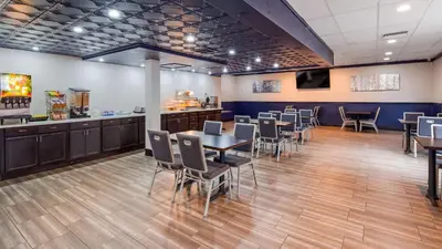 a dining room with tables and chairs and a counter at SureStay Plus Hotel by Best Western Sacramento Cal Expo in Sacramento