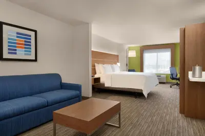 a hotel room with a bed and a blue couch at Holiday Inn Express & Suites Merced - Yosemite Natl Pk Area by IHG in Merced