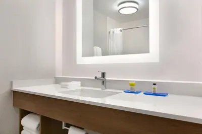 a bathroom with a white sink and a mirror at Holiday Inn Express & Suites Merced - Yosemite Natl Pk Area by IHG in Merced