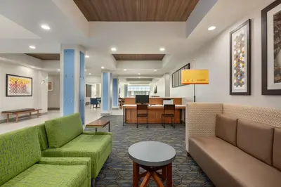 a lobby with couches and a table and a dining room at Holiday Inn Express & Suites Merced - Yosemite Natl Pk Area by IHG in Merced
