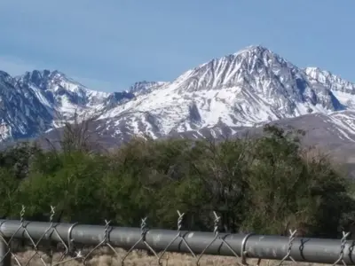 a snow covered mountain in front of a fence at Starlight Motel in Big Pine