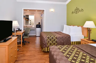 a hotel room with two beds and a desk at Americas Best Value Inn Los Banos in Los Banos