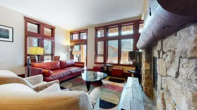 a living room with a couch and a stone wall at Juniper Crest 1 Apartment in Mammoth Lakes