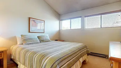 a bedroom with a bed and two windows at Summit 34 Apartment in Mammoth Lakes