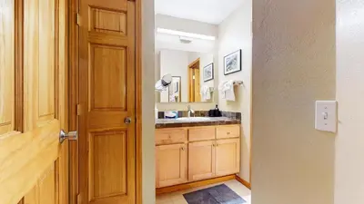 a bathroom with a sink and a wooden door at Summit 55 Apartment in Mammoth Lakes