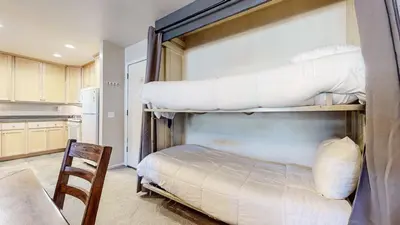 a bedroom with two bunk beds and a kitchen at Summit 55 Apartment in Mammoth Lakes