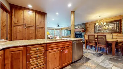a kitchen with wooden cabinets and a dining room with a table at Summit 81 Apartment in Mammoth Lakes