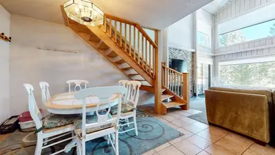 a dining room with a staircase and a table and chairs at Mammoth Reservations in Mammoth Lakes