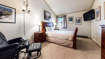 a bedroom with a bed and a chair and a television at Summit 110 Apartment in Mammoth Lakes