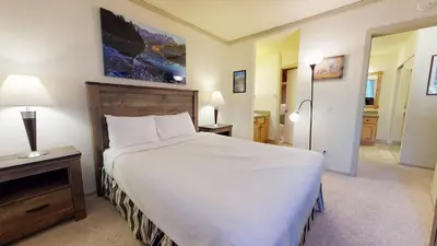 a bedroom with a large white bed and a mirror at Summit 110 Apartment in Mammoth Lakes