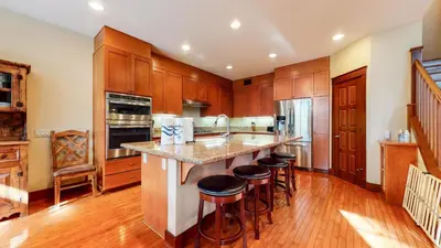 a kitchen with wooden cabinets and a island with bar stools at Timbers 1 Apartment in Mammoth Lakes