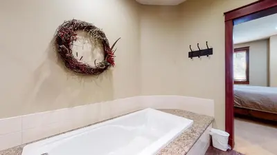 a white tub in a bathroom with a wreath on the wall at Timbers 1 Apartment in Mammoth Lakes