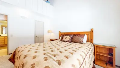 a bedroom with a large bed with a wooden headboard at Wild Flower 6 Apartment in Mammoth Lakes