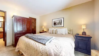 a bedroom with a large bed and a wooden cabinet at Wild Flower 39 Apartment in Mammoth Lakes
