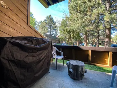 a patio with a trash can and a chair and a stump at Wild Flower 39 Apartment in Mammoth Lakes