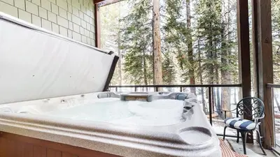 a bath tub on a balcony with a view of trees at Mammoth Reservations in Mammoth Lakes