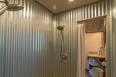 a bathroom with a corrugatedsteel wall with a shower at Miner's Camp in Foresthill